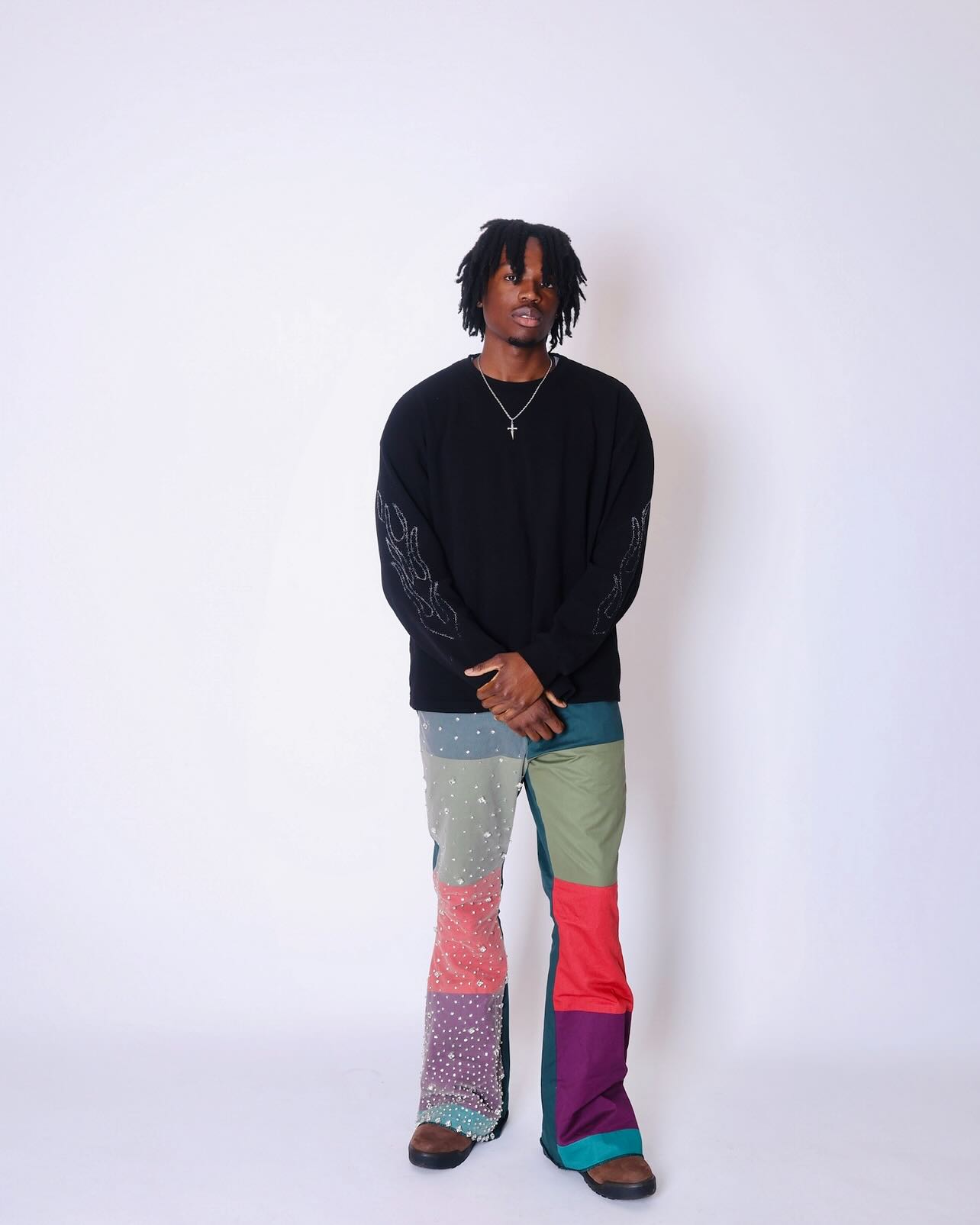 Person wearing a black sweater and colorful pants on a white background