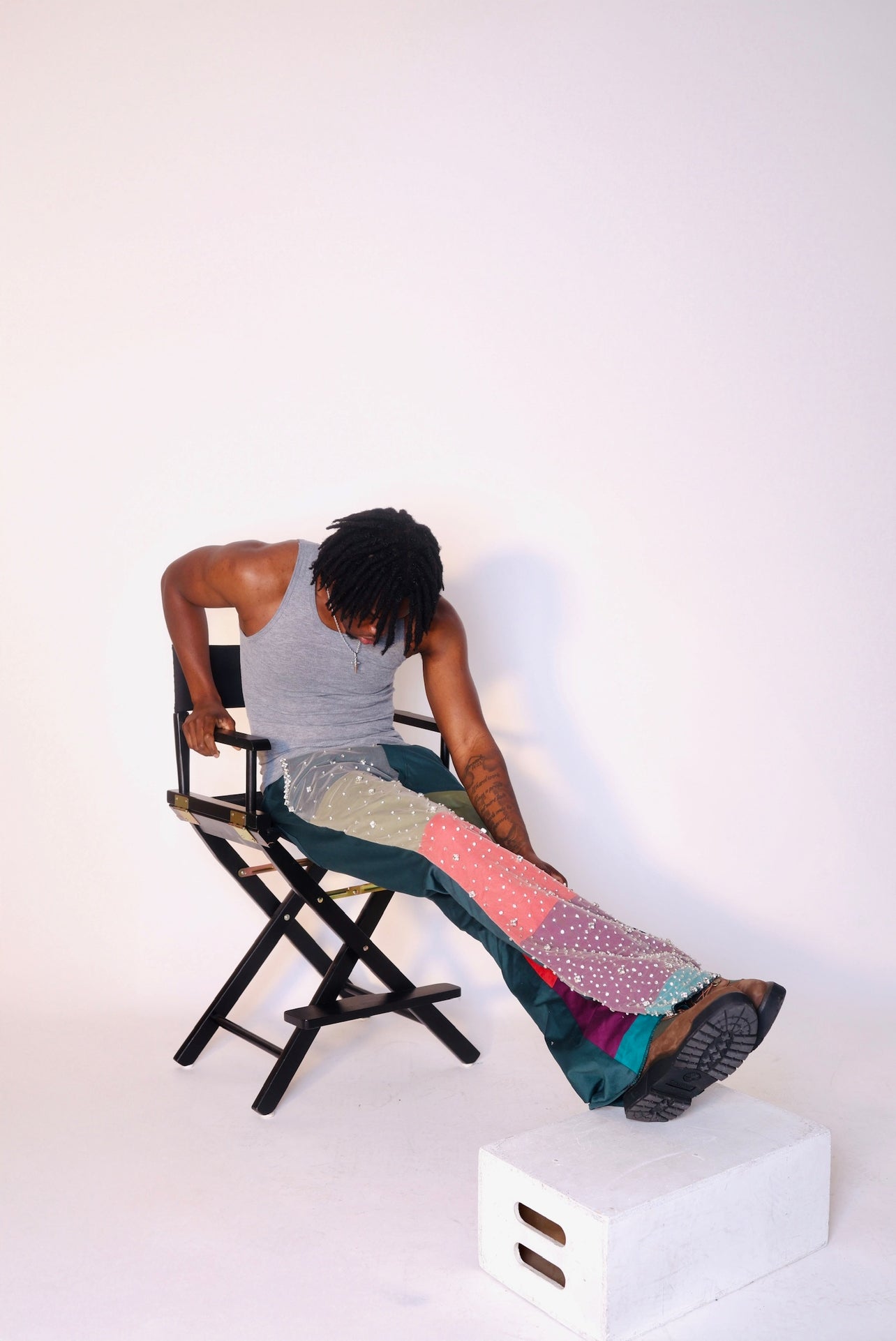 Person sitting on a chair with colorful pants against a white background